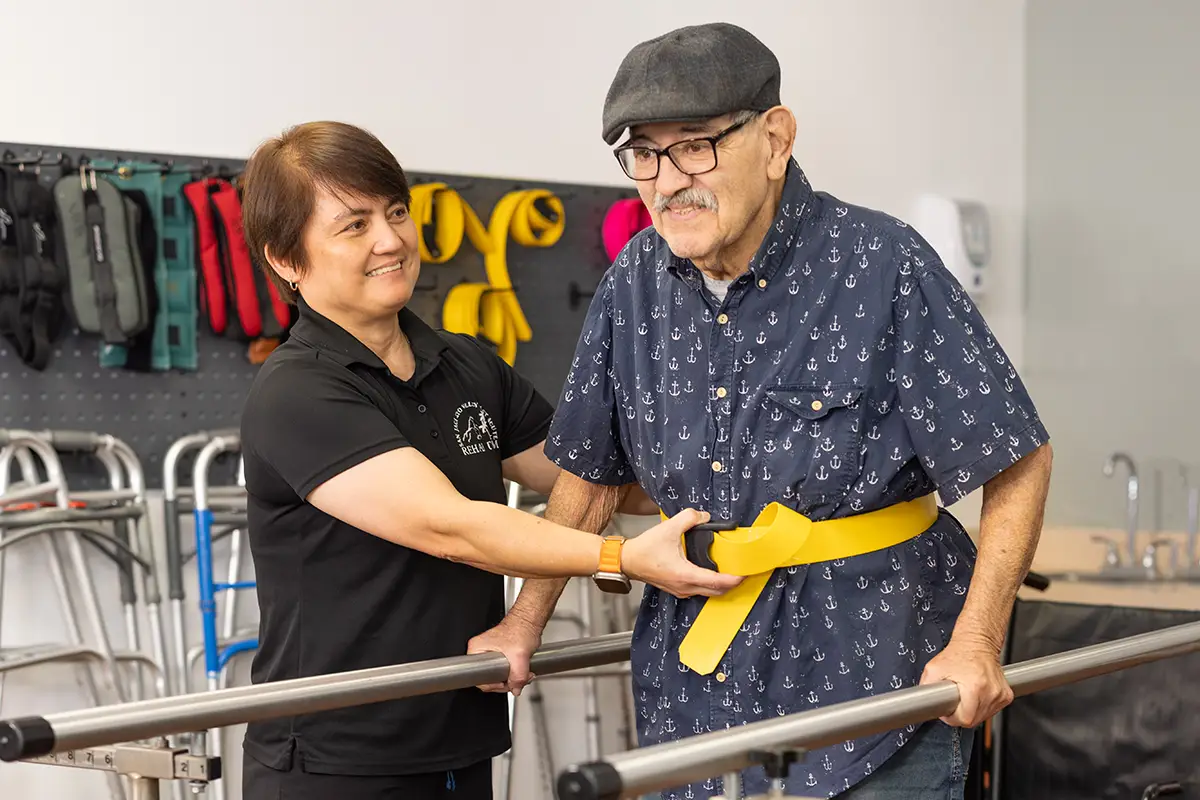 A physical therapist helping an elderly man walk at San Jacinto Valley