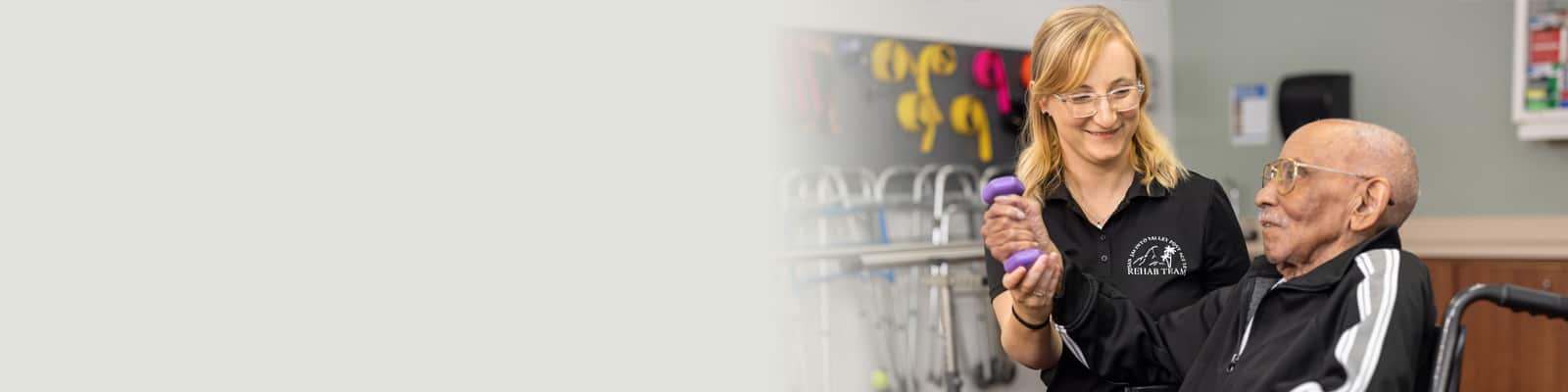 A physical therapist helping a resident to lift weights